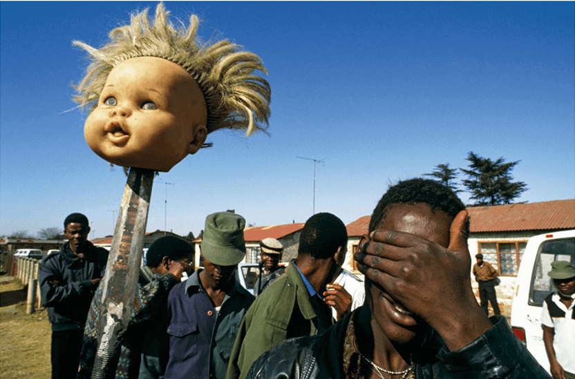 Doll’s Head, Boipatong, 1992, A man holds a white doll’s head on a spear in the angry aftermath of the Boipatong Massacre of June 1992. Forty-five people were killed by Inkatha Freedom Party members, allegedly supported by police, which nearly derailed the negotiations towards a democratic solution to South Africa’s dilemma. 